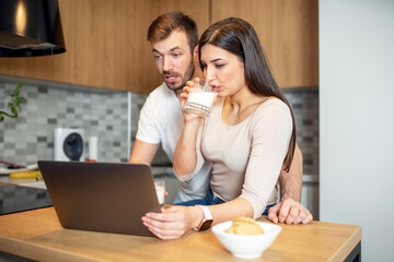 Young couple working on laptop at kitchen