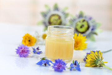 Fototapeta na wymiar Royal jelly surrrounded by fresh flowers- dietary supplement
