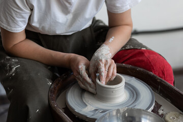 Woman doing pottery on the potter wheel on the workshop