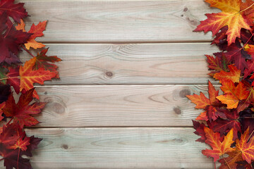 Wooden background with frame of maple leaves. Flat lay. Space for text or inscription in center. Heap of fallen leaves lies on both sides of the table. Top view. Layout. Rustic style concept.