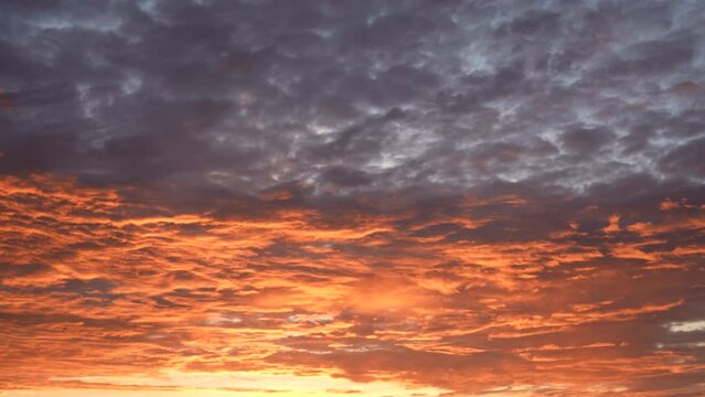 Early morning scenic dramatic cloudscape with colourful orange and purple clouds. 4k video time lapse of rising up morning sun during sunrise time. Scenic natural video background with gradient colors