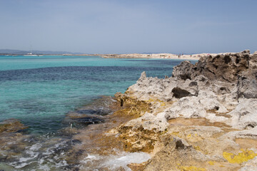 Rocky beach with a turquoise blue sea and waves in spain