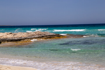 Rocky beach with a turquoise blue sea and waves in spain