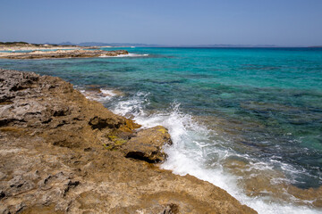 Rocky beach with a turquoise blue sea and waves in spain