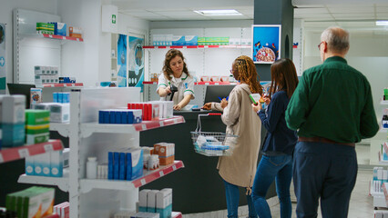 Diverse customers paying for medicaments and drugs with mobile phone nfc, smartwatch or credit card at pharmacy counter. Buying pharmaceutical healthcare products and vitamins at drugstore.