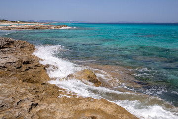 Rocky beach with a turquoise blue sea and waves in spain