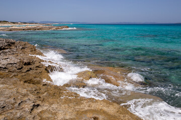 Rocky beach with a turquoise blue sea and waves in spain