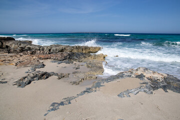 Rocky beach with a turquoise blue sea and waves in spain