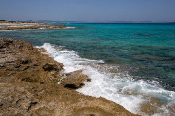 Rocky beach with a turquoise blue sea and waves in spain
