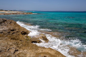 Rocky beach with a turquoise blue sea and waves in spain