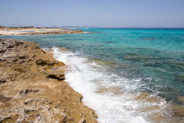 Rocky beach with a turquoise blue sea and waves in spain