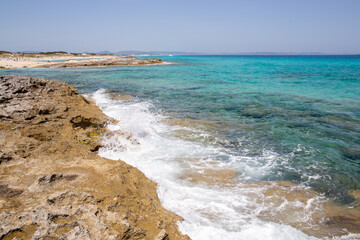 Rocky beach with a turquoise blue sea and waves in spain
