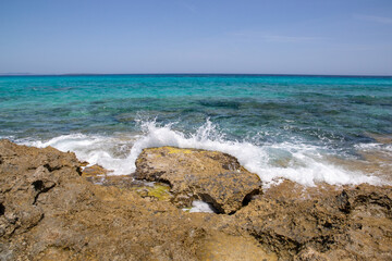 Rocky beach with a turquoise blue sea and waves in spain