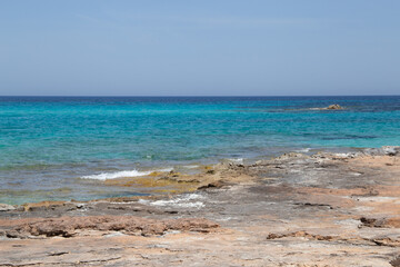 Rocky beach with a turquoise blue sea and waves in spain