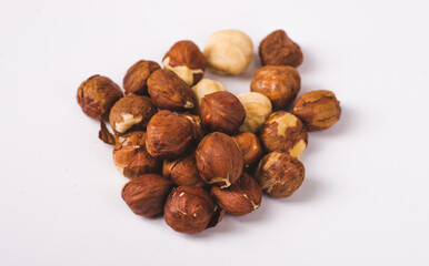 Pile of roasted peeled hazelnuts close-up isolated on white background. Lots of brown nut seeds, healthy vegan and vegetarian food