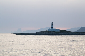 Obraz premium Lighthouse on a Mediterranean island during sunset.