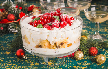 Christmas trifle with recycling panettone and cream with berries on festive table.