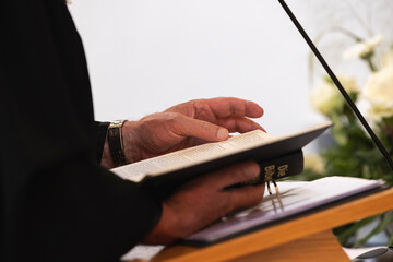 Ein Pfarrer steht am Altar und predigt mit Bibel in der Hand