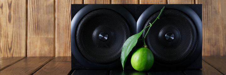 Two square wooden audio speakers - acoustic system and fresh lime on a wooden background made of...