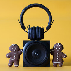 Audio speaker, headphones and funny gingerbread men on a yellow background. The concept of family...