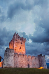 Fototapeta premium Ancient old Fortress Ross Castle ruin with a lake, green grass and orange clouds. Killarney national park, co Kerry, Ireland. High quality photo