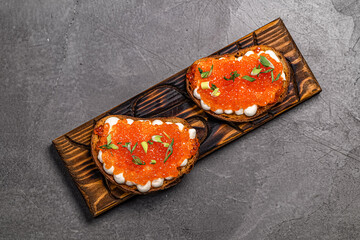 bread with red caviar on a wooden board in a restaurant
