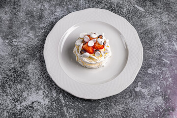 dessert Anna Pavlova on a white plate on a gray background in a restaurant