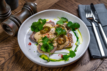 dish tongue sliced with jalapenos in a restaurant