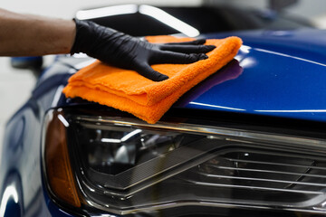 Hand car drying with microfiber in detailing auto service. Cleaner worker dry body car after...