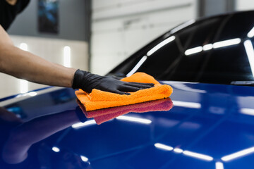Hand car drying with microfiber in detailing auto service. Cleaner worker dry body car after...