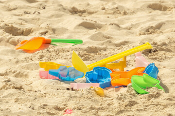 Children's toys are scattered on the sea sandy beach. Colored spatulas and molds on the sand. Children's games in the sandbox.