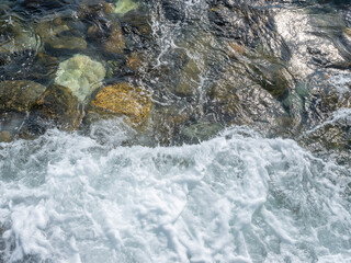 Abstract photo of a rocky beach covered by a wave.