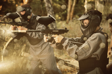 Fototapeta premium Paintball players aiming and shooting with guns at opposing team outdoors
