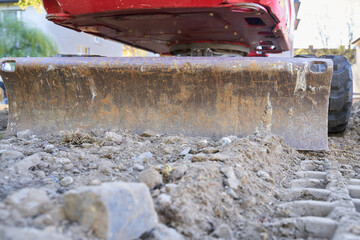 Excavator on a construction site photographed from behind at ground level. Dozer blade is visible. Space for text. © Francesco