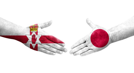 Handshake between Japan and Northern Ireland flags painted on hands, isolated transparent image.