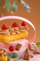  custard cakes.Eclairs cakes with chocolate cream and raspberries on a brown background.Choux pastry.