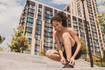 Fototapeta na wymiar Curly-haired girl tying her sneakers during exercising