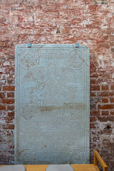 Germany, Wismar - July 13, 2022: St. Georgen Kirche, church. Historic Homo Flos tomb stone of Joachim Bansovic featuring smiling angel and flowers set against ruinous brick wall