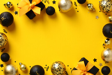 Yellow Christmas background with black gift boxes decorated yellow ribbon bow, shiny golden and black baubles, Xmas balls, confetti. Festive New Year banner template, Christmas greeting card design.