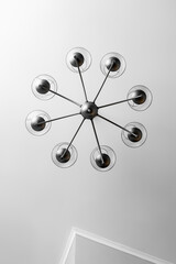 A round chandelier of several lamps against a light ceiling, full frame, bottom view