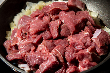 fresh raw chopped meat and onion in a frying pan