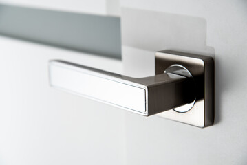 modern metal door handle on white door