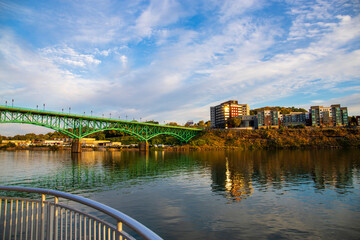 a gorgeous autumn landscape along the Tennessee River with the Gay Street Bridge over the water with blue sky and clouds at sunset in Knoxville Tennessee USA - obrazy, fototapety, plakaty
