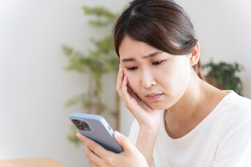 スマホを見て落ち込む女性