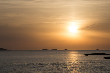 Sunset on the island of Ibiza with the sun setting on the horizon and orange colors in the sky