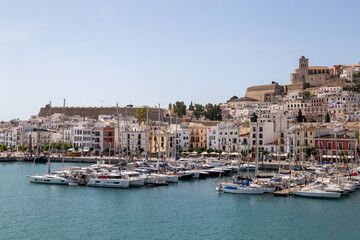 ibiza city seen from the sea, port with boats on the pier of ibiza with a church in the background