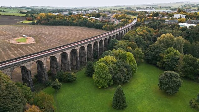 Drone footage of the Penistone Railway Station and Railway Viaduct near Barnsley, South Yorkshire. Showing a ploughed field, bridge, woodland and railway tracks.