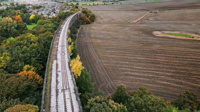Drone footage of the exceptional Penistone Railway Station and Viaduct near Barnsley, South Yorkshire. Showing a ploughed field, bridge, woodland and railway tracks.