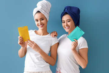 Beautiful young women with facial masks on blue background