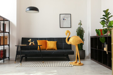 Interior of room with comfortable sofa and golden flamingo near light wall